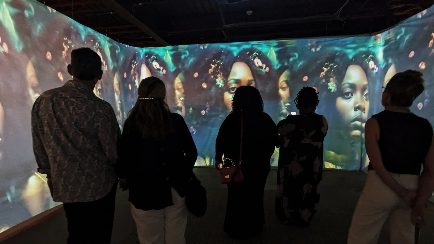 Visitors surrounded by ILE OMI projections across three walls