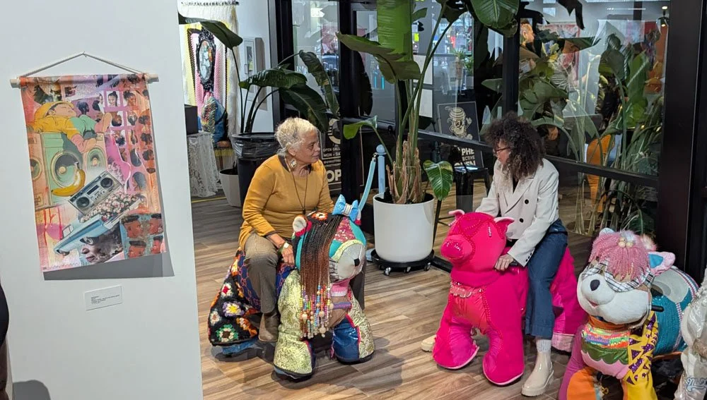 Visitors riding colorful animal sculptures in the Ride the Animals exhibition